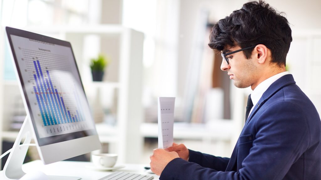 An SEO expert in a suit examines a computer screen displaying a chart, reflecting his analytical skills and professionalism.